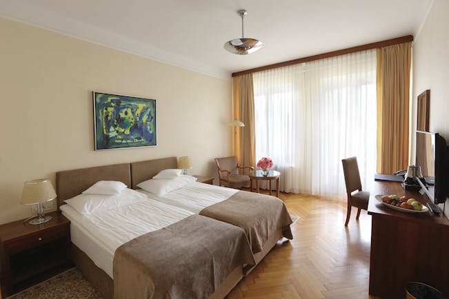 Double room with balcony at the Vila Bled hotel, with a neutral colour scheme and television 