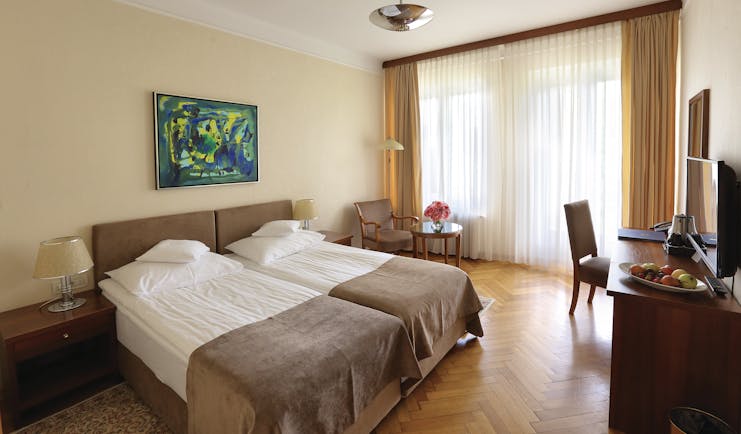Double room with balcony at the Vila Bled hotel, with a neutral colour scheme and television 