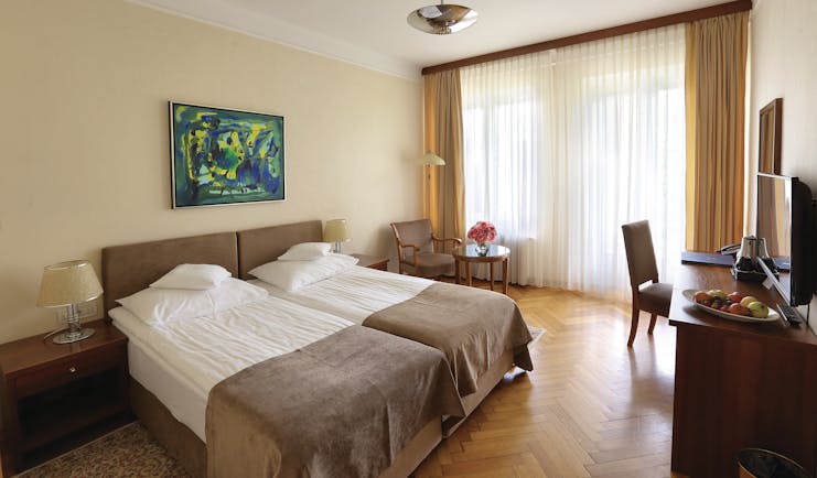 Double room with balcony at the Vila Bled hotel, with a neutral colour scheme and television