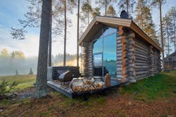Arctic Retreat cabin exterior with private deck and woodpile, trees and wood in background