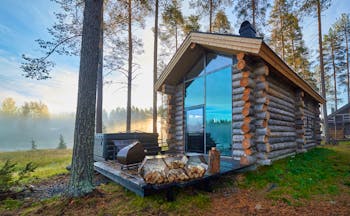Arctic Retreat cabin exterior with private deck and woodpile, trees and wood in background