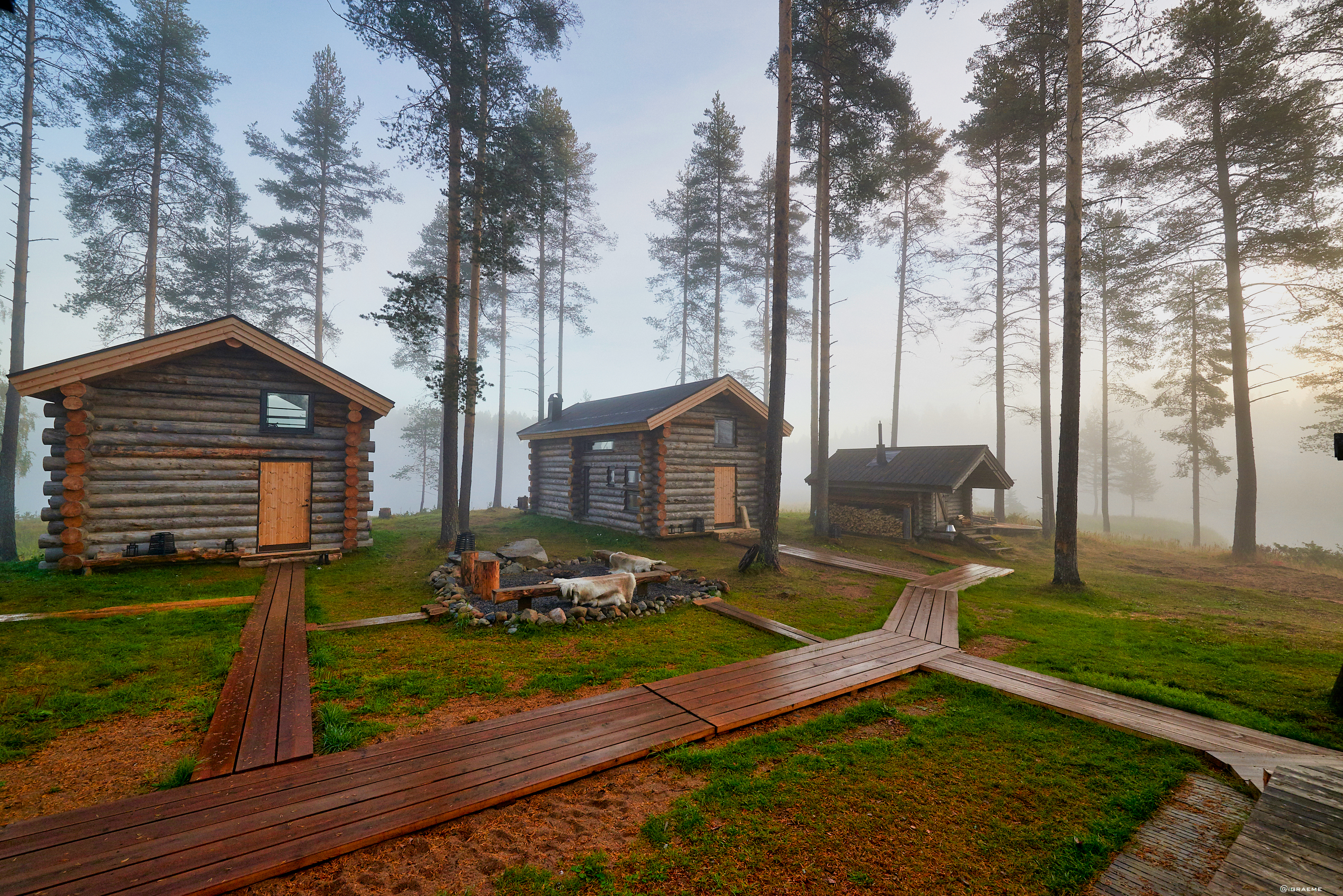 Arctic Retreat log cabins exteriors, set in the woods with wooden pathway to and from
