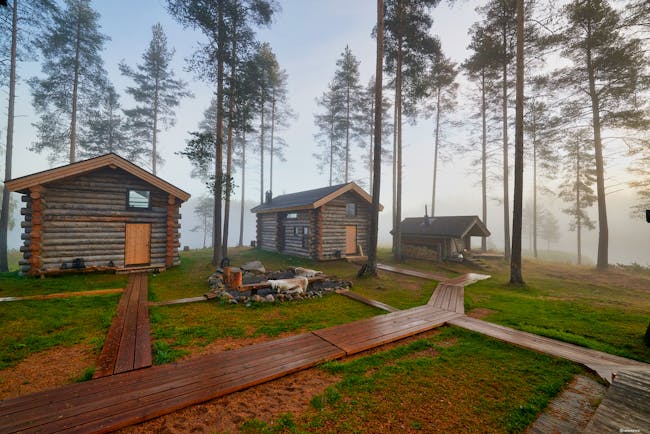Arctic Retreat log cabins exteriors, set in the woods with wooden pathway to and from