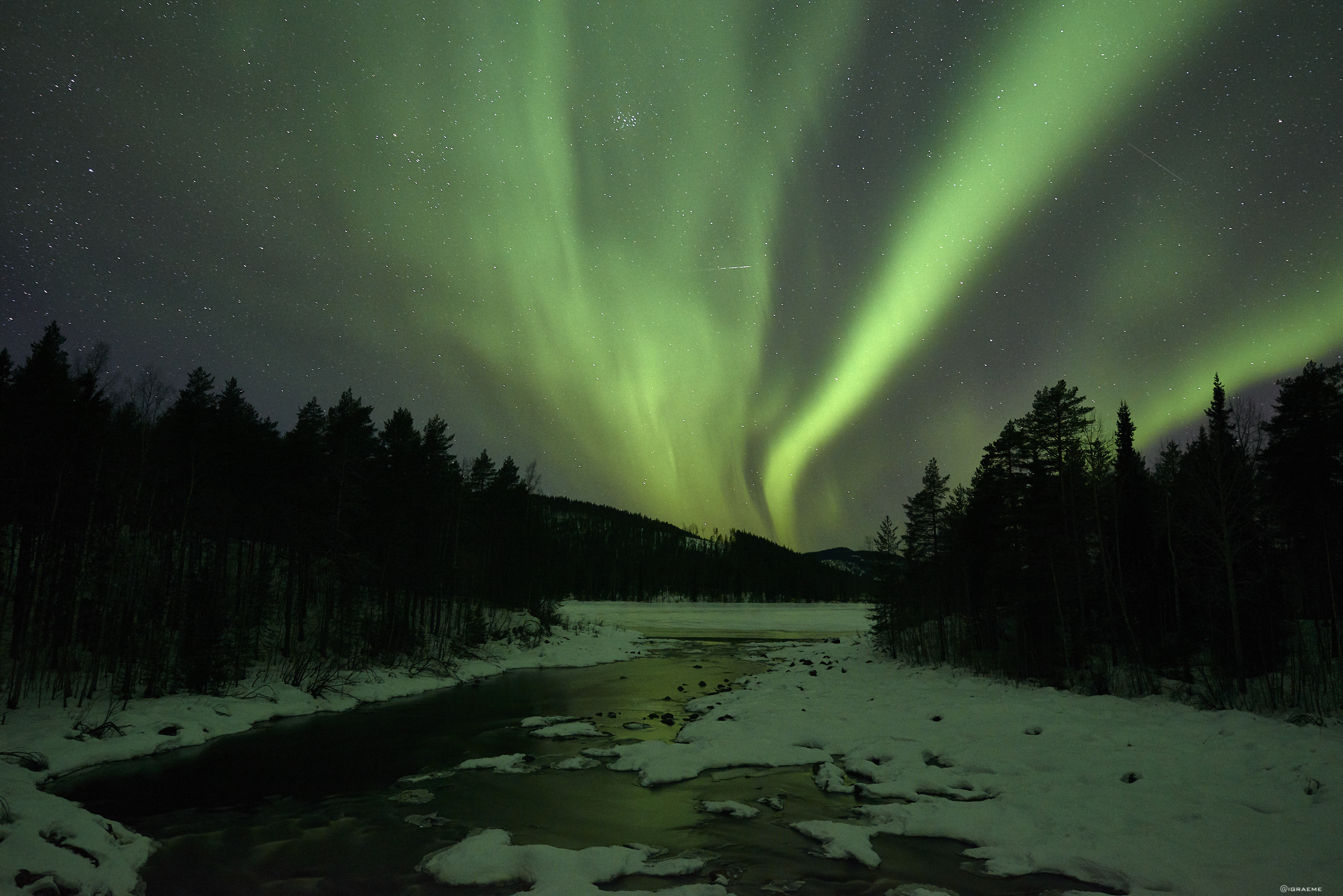 Arctic Retreat northern lights over icy river and woodland