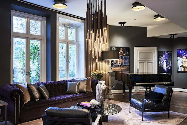 Hotel Lydmar living room, purple velvet sofa, leather armchairs, chandelier, posters on wall
