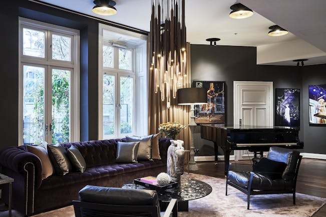 Hotel Lydmar living room, purple velvet sofa, leather armchairs, chandelier, posters on wall