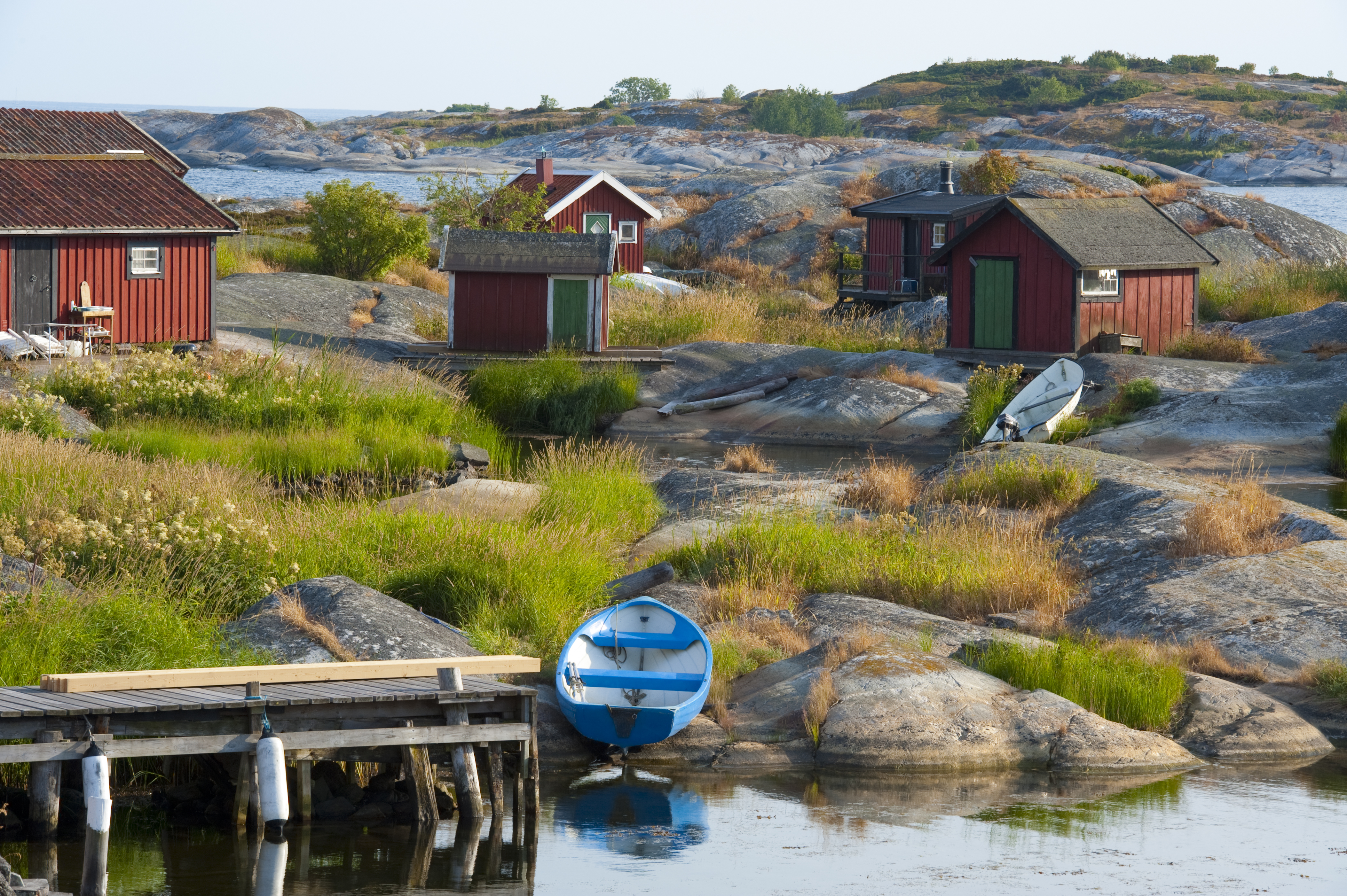 Burnt orange cottages and fishing boats by the water's edge on the Swedish archipelago