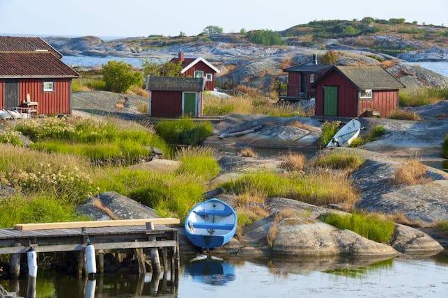 Burnt orange cottages and fishing boats by the water's edge on the Swedish archipelago