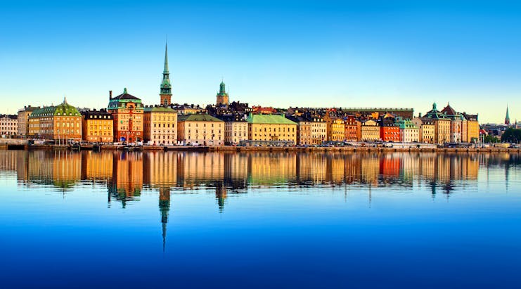 Yellow and red buildings with spire reflected in water