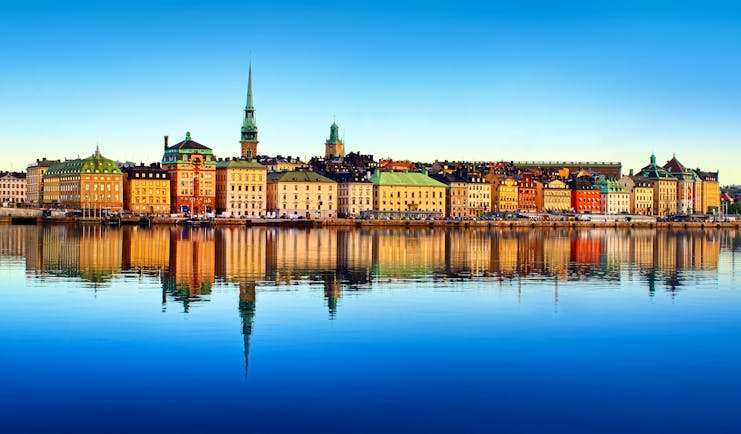 Yellow and red buildings with spire reflected in water