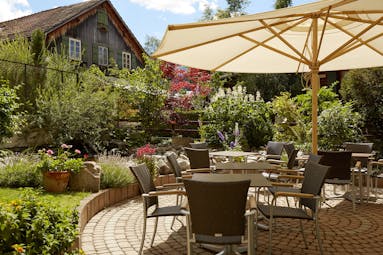 Gstaaderhof chairs and tables with umbrellas in garden with old chalet behind