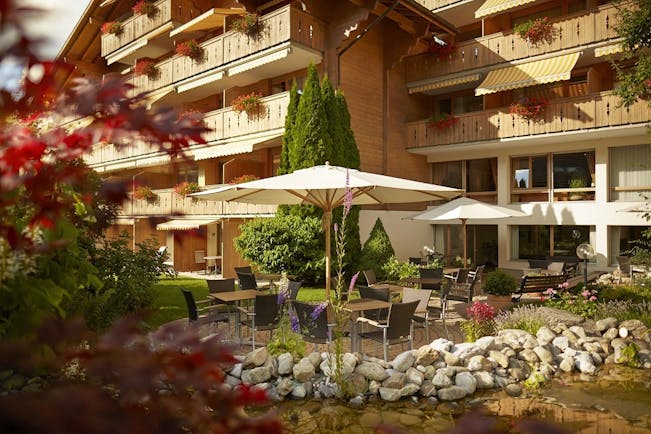 Gstaaderhof wooden chalet hotel with balconies and umbrellas in garden