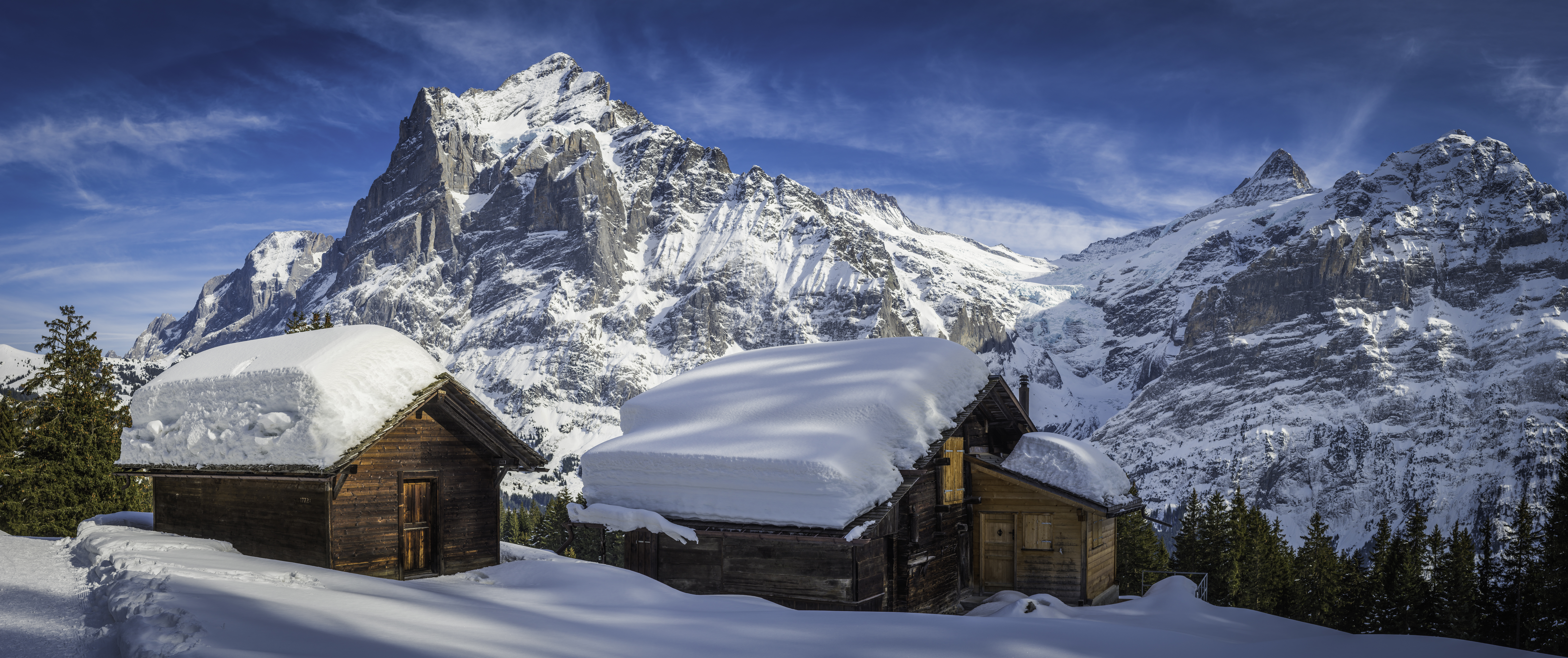 Alpine wooden houses with thick snow on roof at Grindelwald