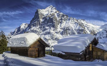 Alpine wooden houses with thick snow on roof at Grindelwald