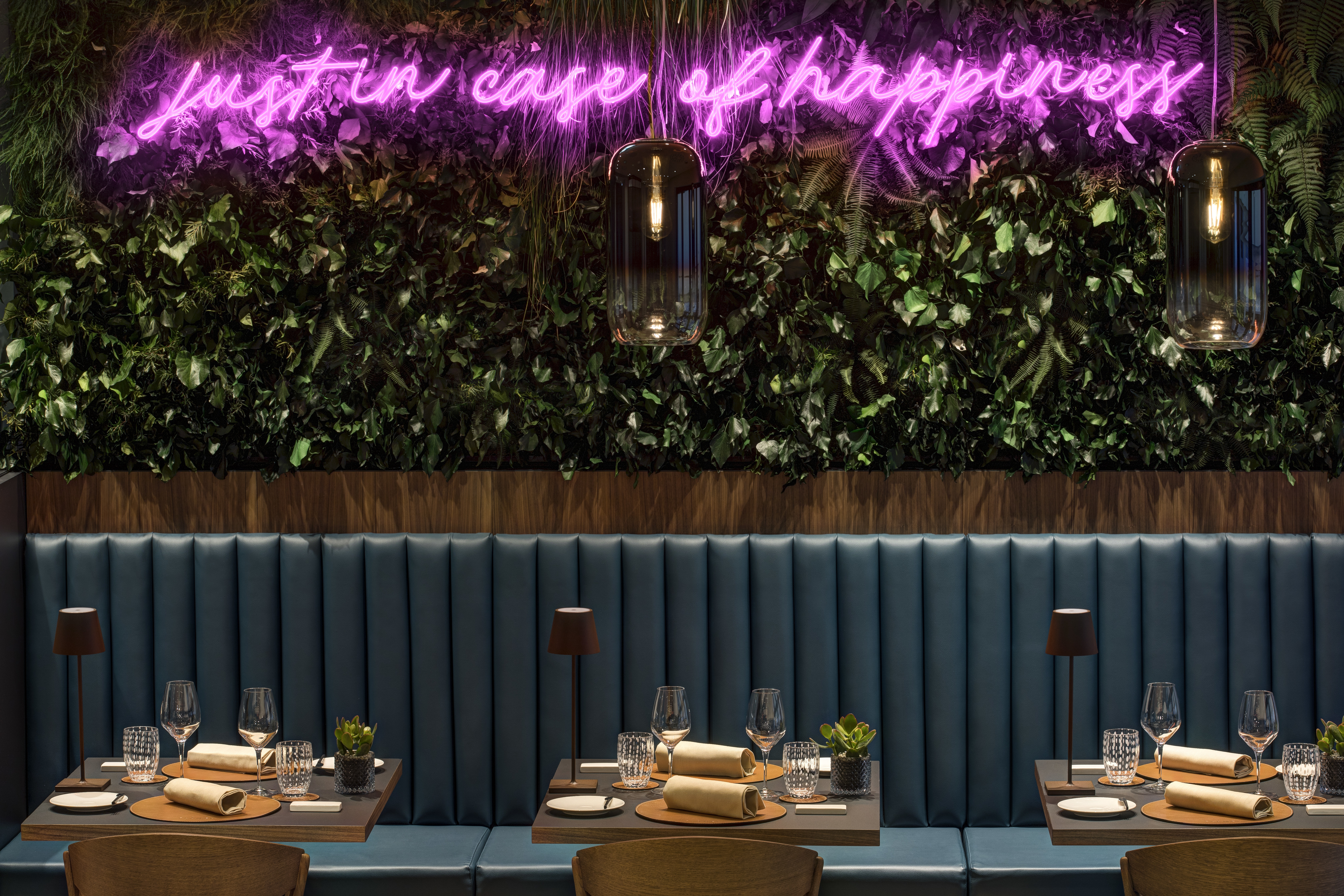 Hotel Lugano Dante bar, tables with drinks and napkins, bench seating, green leafy wall installation