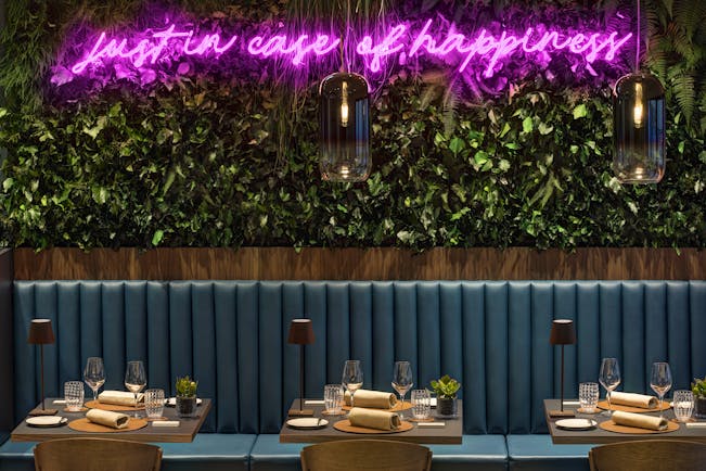 Hotel Lugano Dante bar, tables with drinks and napkins, bench seating, green leafy wall installation