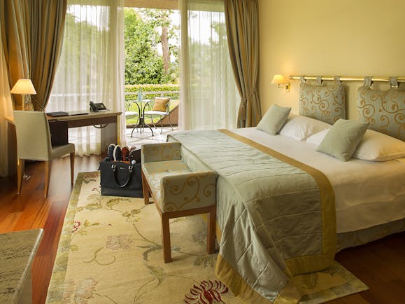 Villa Principe Leopoldo bedroom with green and beige furnishings and greenery outside