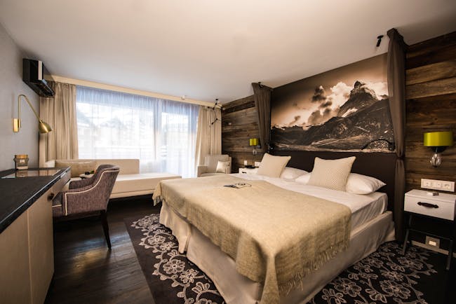 Hotel Alpenhof Zermatt beige and brown room with wood and flowerd carpet under bed