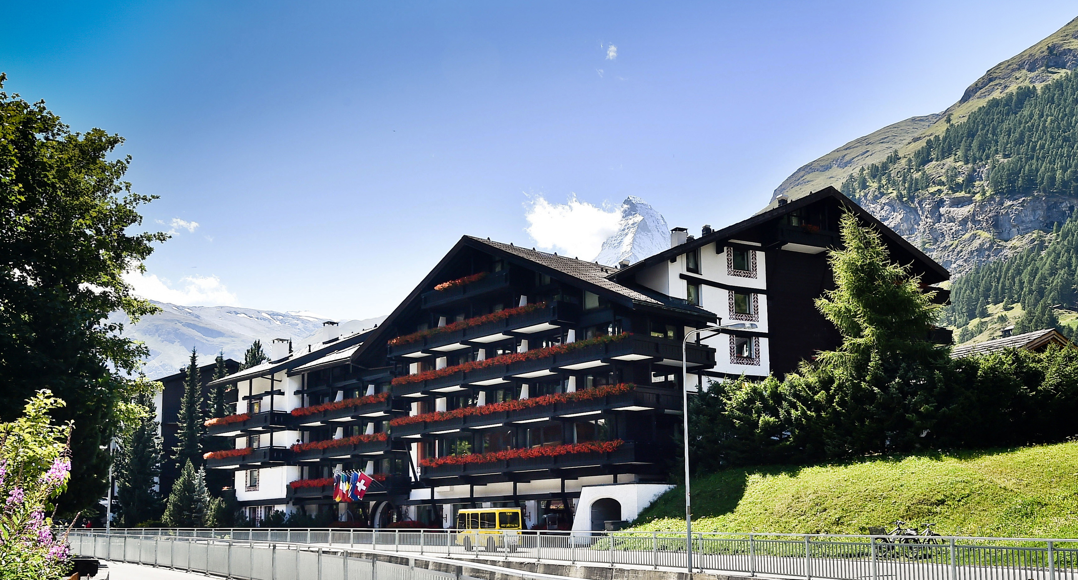 Hotel Alpenhof Zermatt exterior of large chalet hotel with grassy bank newarby