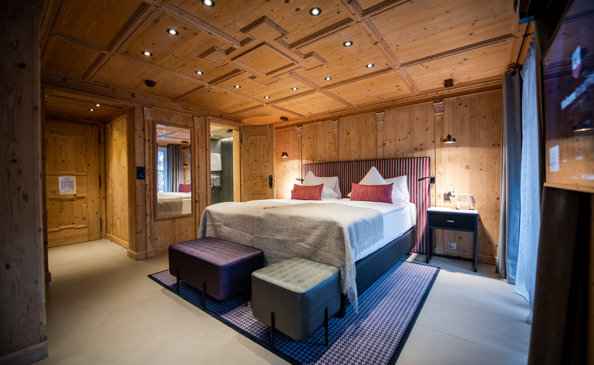 Romantik Hotel Julen Zermatt bedroom with lare bed, cushions and wooden ceilings and walls