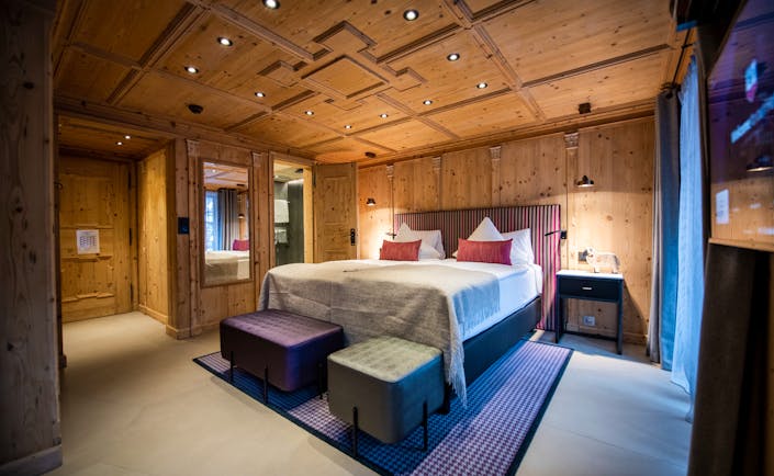 Romantik Hotel Julen Zermatt bedroom with lare bed, cushions and wooden ceilings and walls