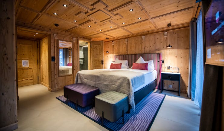 Romantik Hotel Julen Zermatt bedroom with lare bed, cushions and wooden ceilings and walls