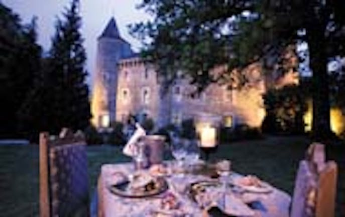 Chateau Codignat Auvergne outdoor dining area at night overlooked by the chateau