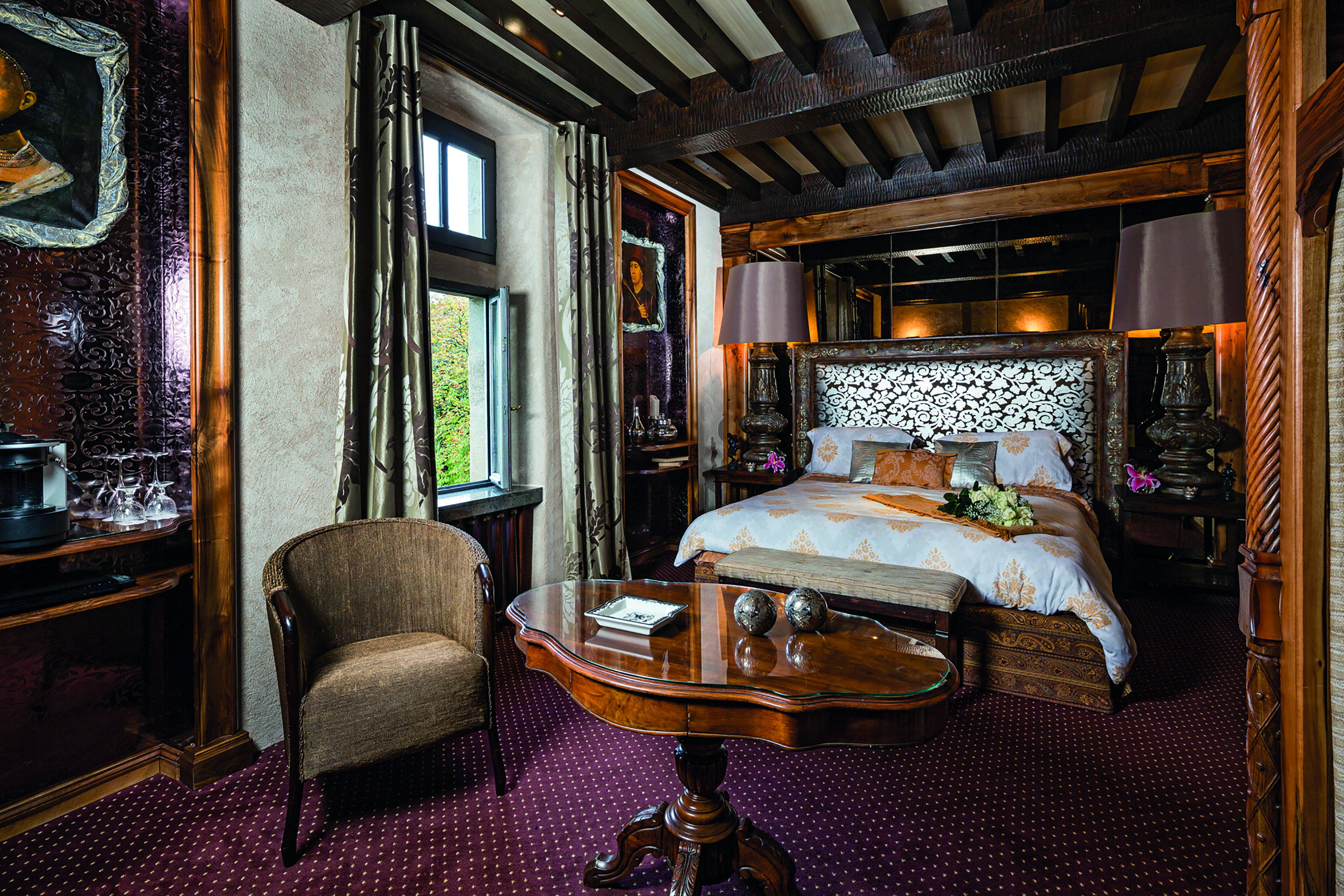 Chateau Codignat Auvergne prestige bedroom with exposed wooden beams and carved wooden bed and artwork