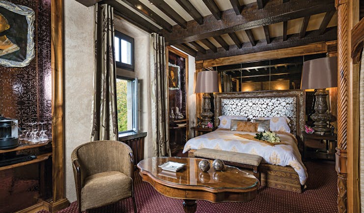 Chateau Codignat Auvergne prestige bedroom with exposed wooden beams and carved wooden bed and artwork