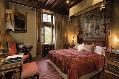 Chateau Codignat Auvergne traditional bedroom with carved wooden bed and tapestry on the wall