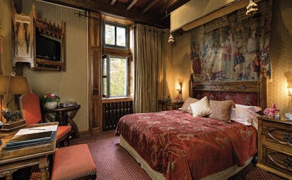 Chateau Codignat Auvergne traditional bedroom with carved wooden bed and tapestry on the wall