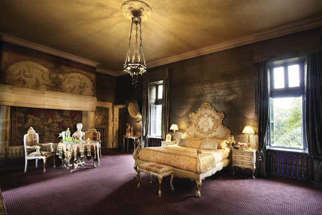 Chateau Codignat Auvergne suite ornate bed in room with tapestry on the wall next to a table with champagne
