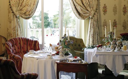 Chateau de Mirambeau breakfast room, indoor dining area with armchairs, tables set with afternoon tea, traditional grand architecture
