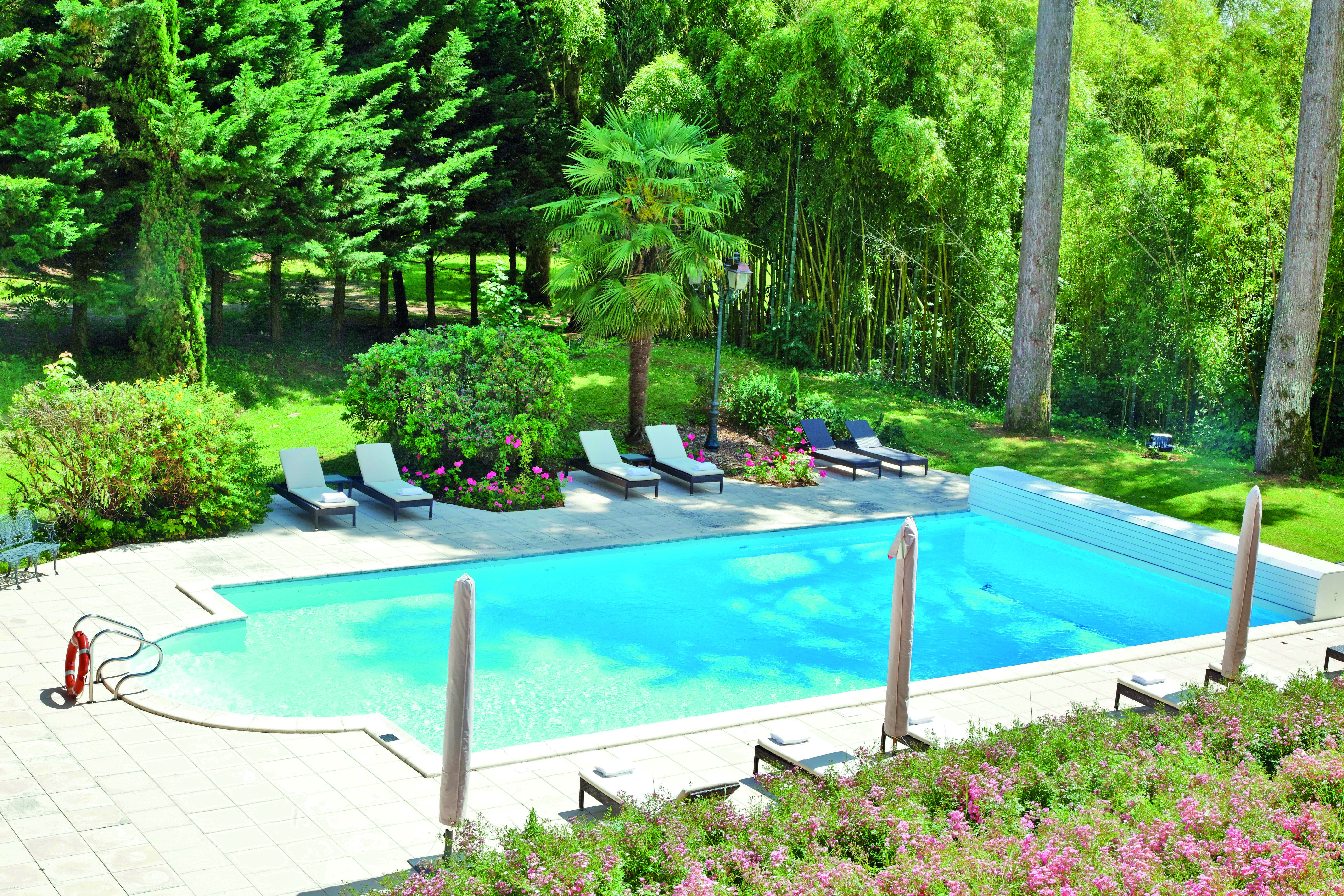 Chateau de Mirambeau outdoor pool, sun loungers, surrounded by lawns, wooded area