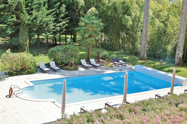 Chateau de Mirambeau outdoor pool, sun loungers, surrounded by lawns, wooded area
