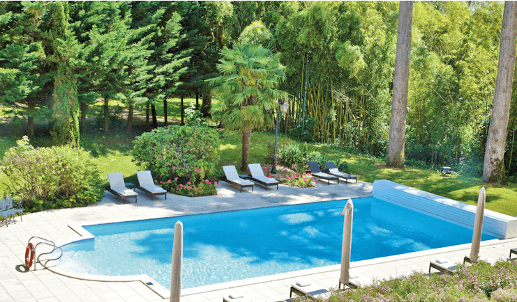 Chateau de Mirambeau outdoor pool, sun loungers, surrounded by lawns, wooded area