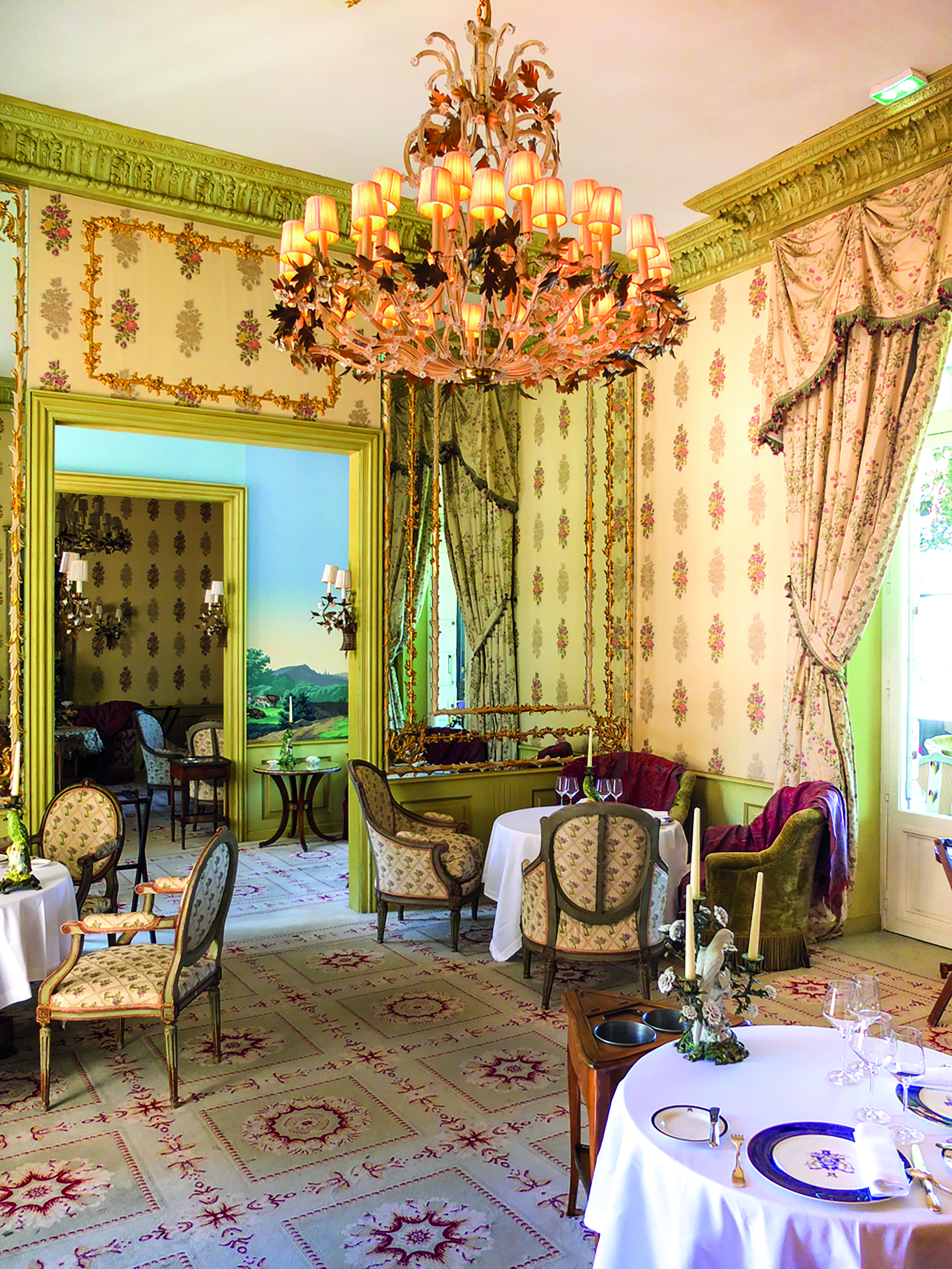 Dining area with large chandelier, drapes and tables set up 