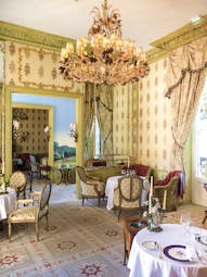Dining area with large chandelier, drapes and tables set up 