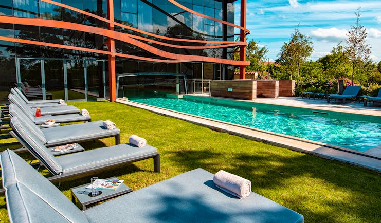 Outdoor swimming pool and grass with grey loungers Chais Monnet Cognac