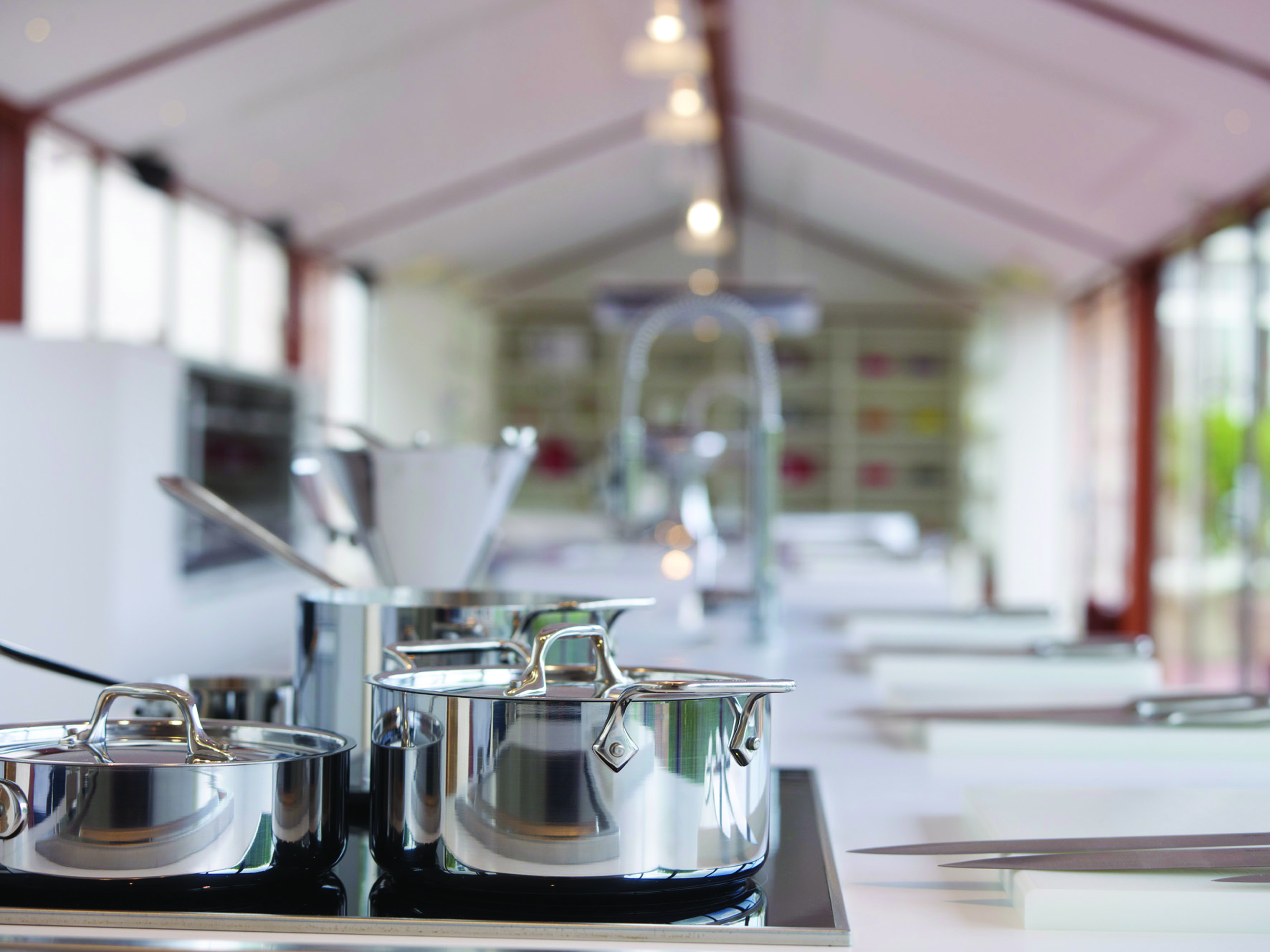 Silver pans on a stove in large white kitchen
