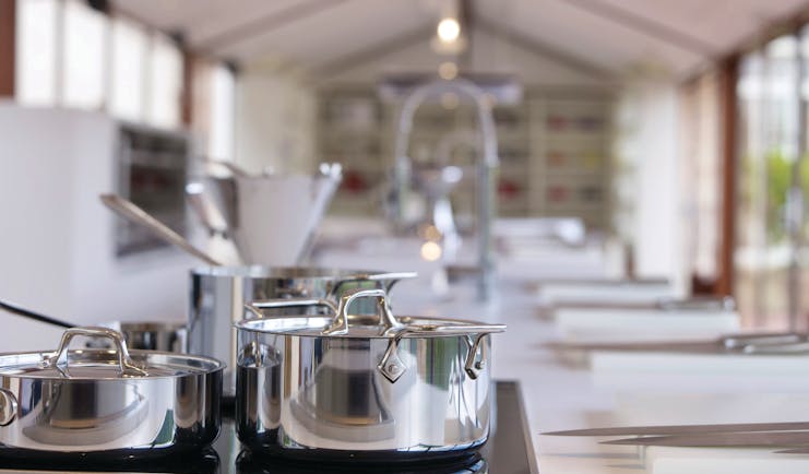 Silver pans on a stove in large white kitchen