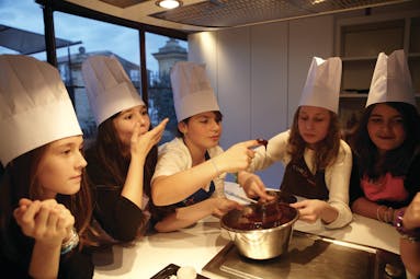 Group of ladies with chefs hats looking at cooking things
