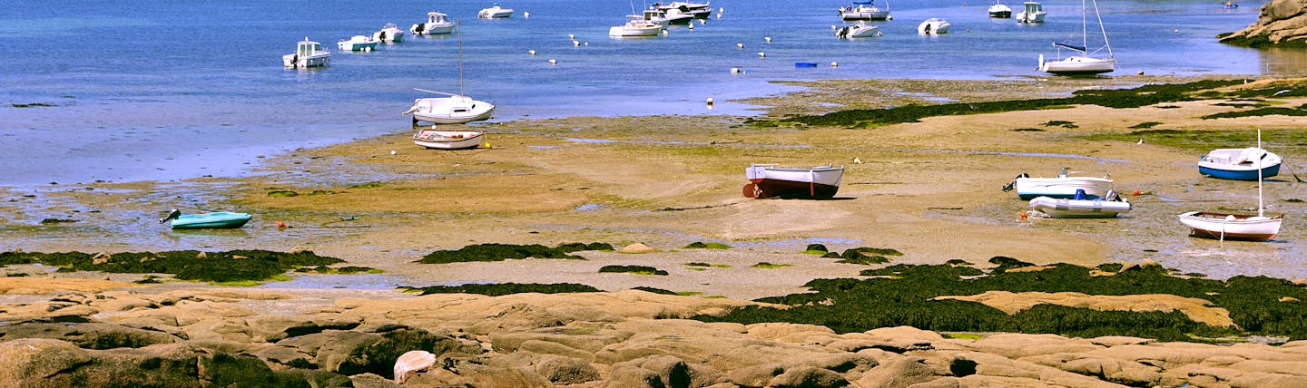 Coast with beach and boats on pink granite coast near Trebeurden