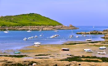 Coast with beach and boats on pink granite coast near Trebeurden