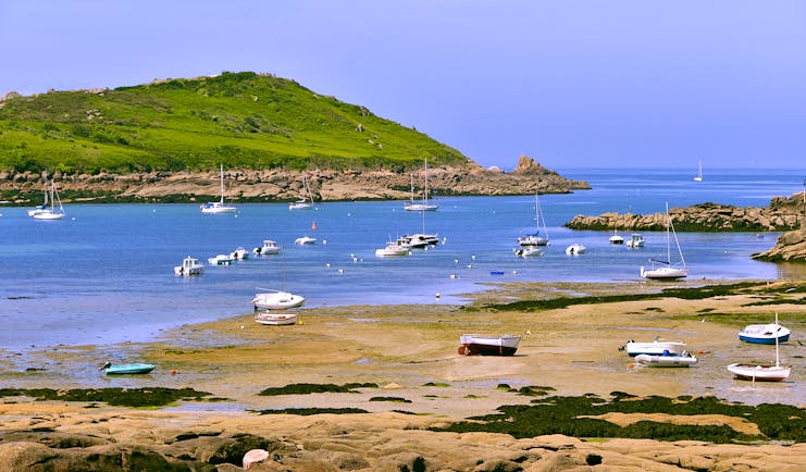Coast with beach and boats on pink granite coast near Trebeurden