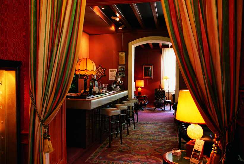 Bar with burgundy colour scheme and lamp shades around the room for light 