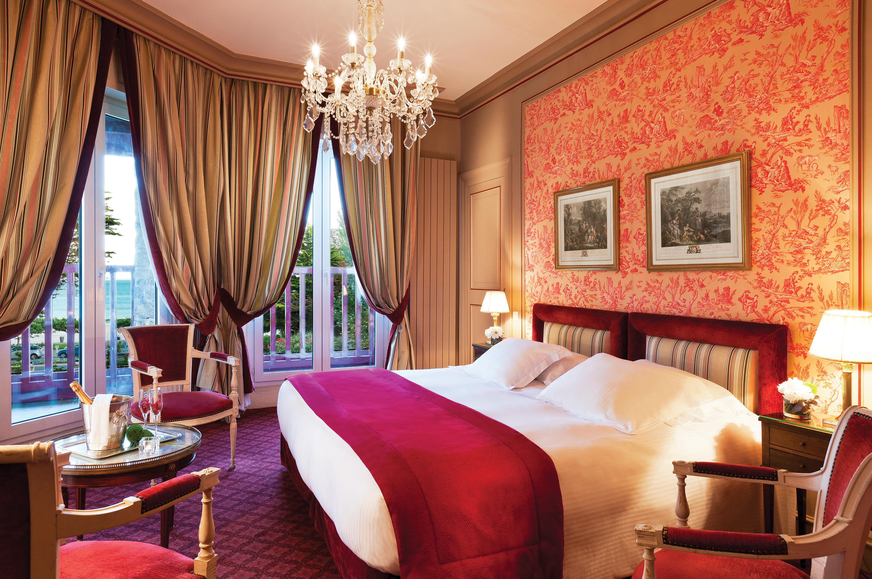 Bedroom with pink colour scheme, draping curtains, a large chandelier and double bed