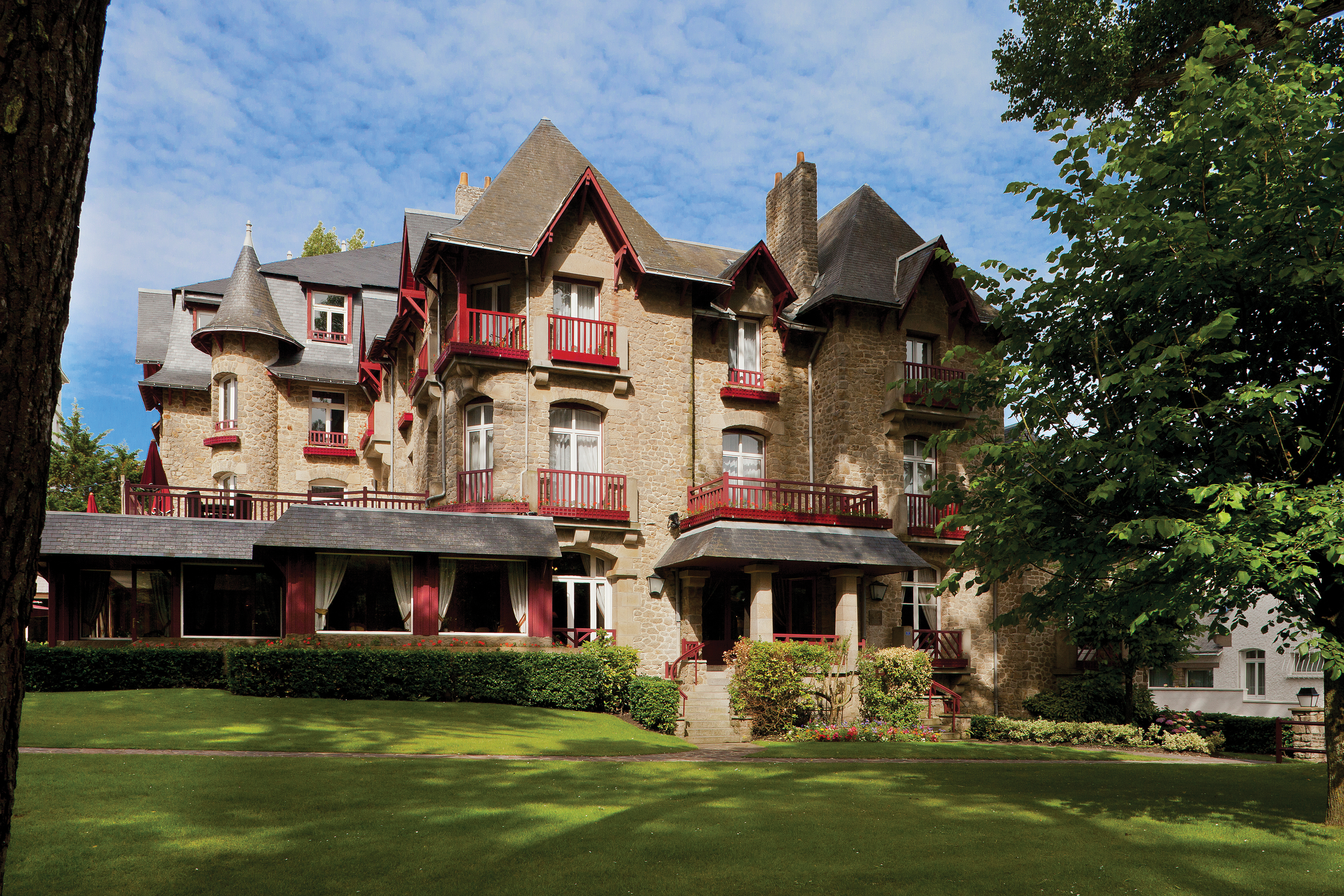 Exterior view of the stone hotel building with red balconys 