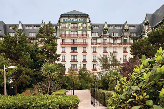 Hotel Hermitage Barriere Brittany exterior garden white building with blue tiled sign balconies and greenery