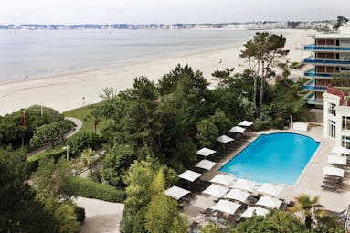 Hotel Hermitage Barriere Brittany outdoor pool facing onto the beach with sun loungers and umbrellas